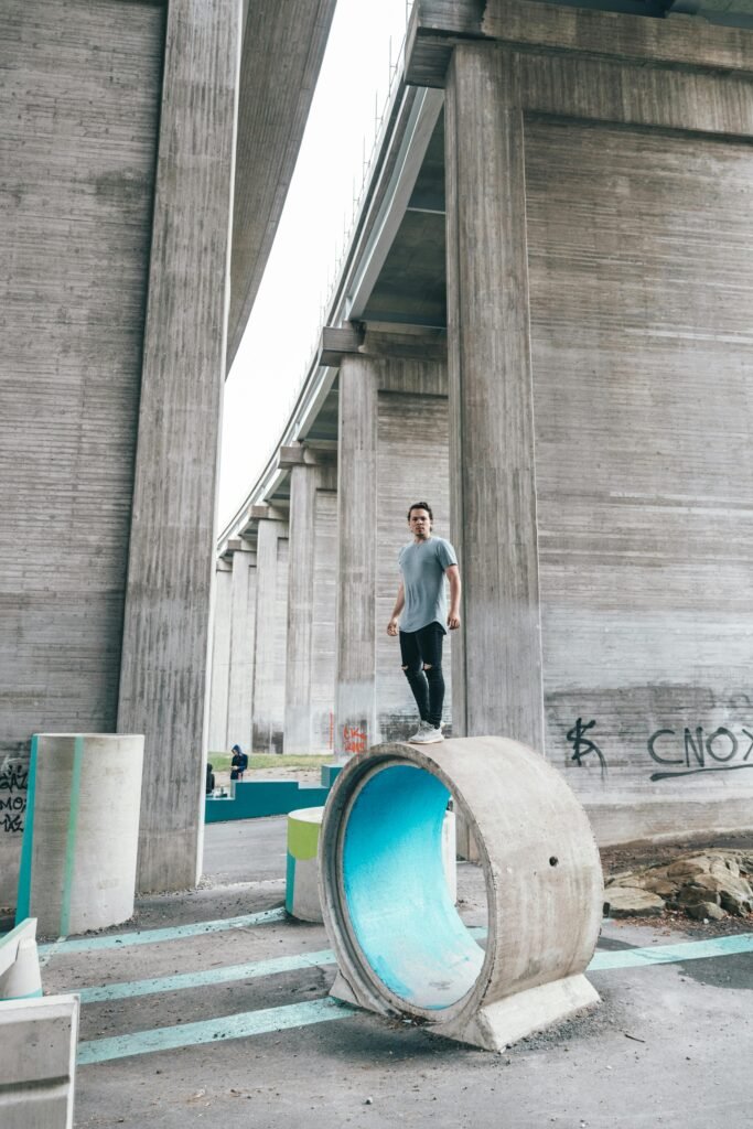 pexels-photo-4388288-4388288 Full length of young man wearing sportswear doing parkour tricks under concrete high bridge