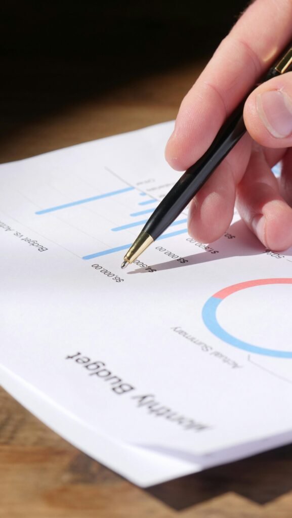 pexels-photo-7054413-7054413 Close-up of hand analyzing data on a monthly budget document with graphs and charts.